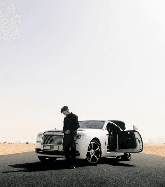 Rohan Robert beside a white Rolls-Royce in the desert